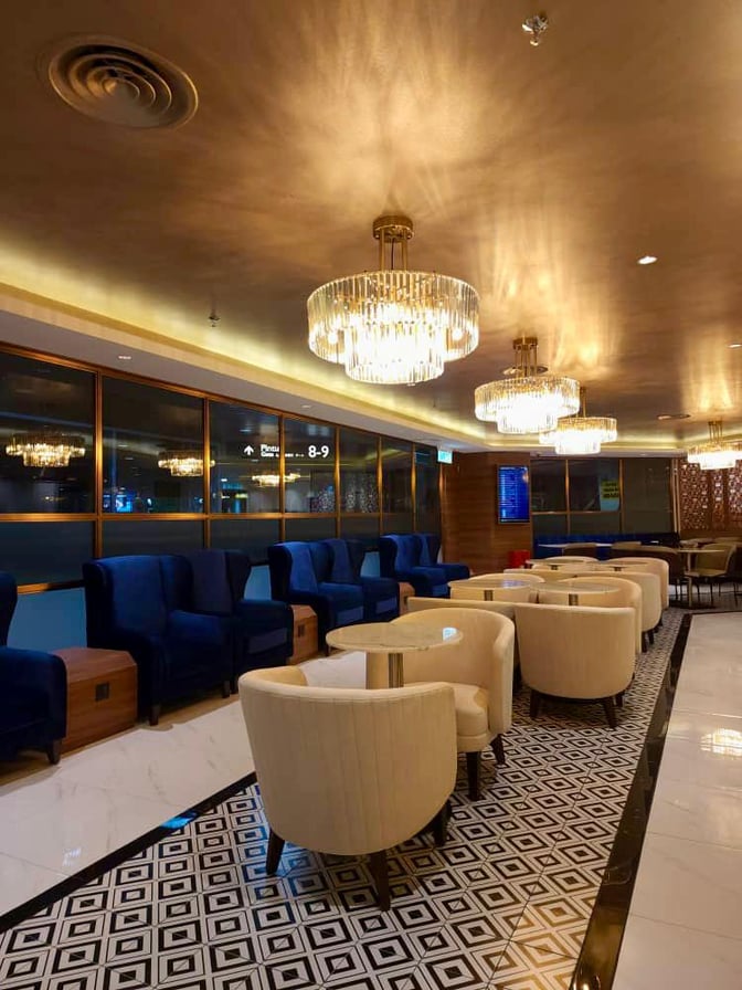 The Travel Club Lounge at Kuching International Airport features comfortable seating with tables, providing a relaxing space for travelers.