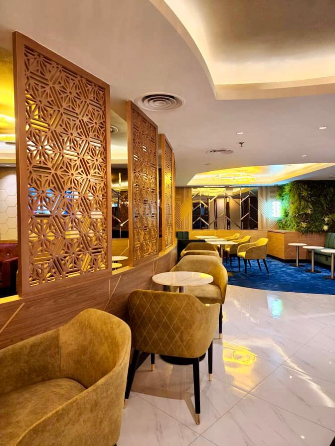 The Travel Club Lounge at Kuching International Airport features seating with small tables, decorative partitions, and a relaxed atmosphere.
