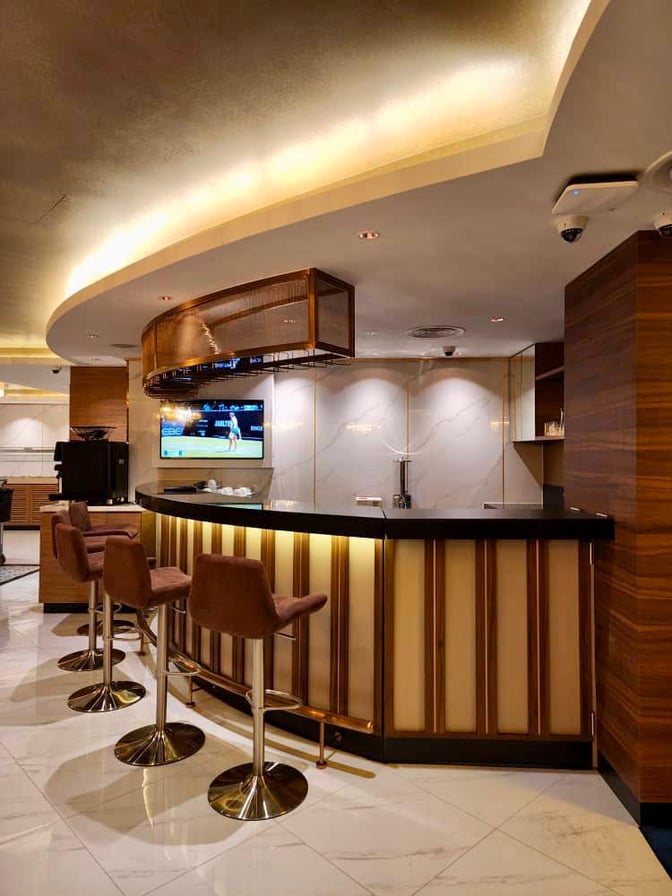 The Travel Club Lounge at Kuching International Airport features a bar with high stools and a television for entertainment.