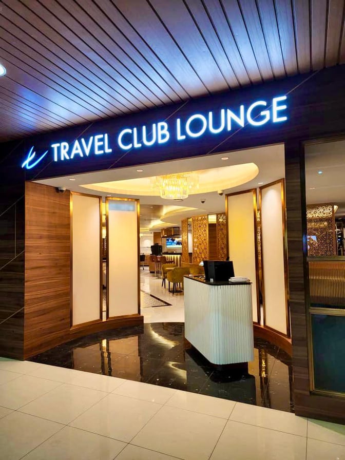 The entrance to the Travel Club Lounge at Kuching International Airport features a reception desk and leads to a seating area.