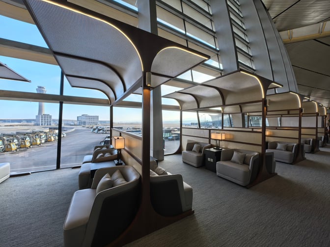 The First Class Lounge V6 at Kunming Changshui International Airport features semi-private seating with airport runway views through large windows.
