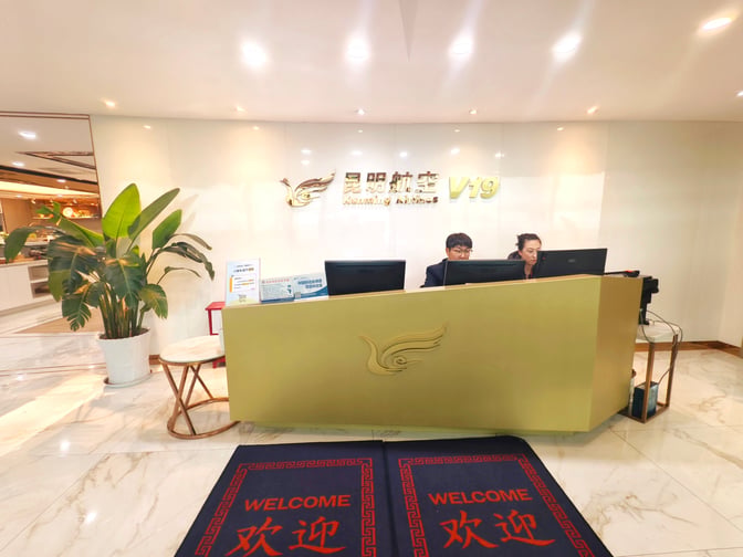 The KunMing Airline V19 Lounge entrance at Kunming Changshui International Airport features a reception desk with staff ready to assist guests.