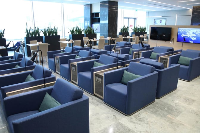 The Al Mubarakiya Lounge at Kuwait International Airport features individual seating with power outlets and a view of the tarmac.