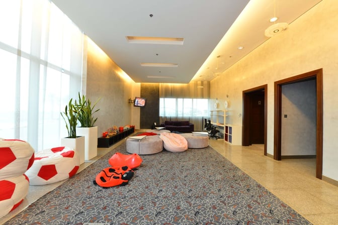 The children's play area in Pearl Lounge at Kuwait International Airport features bean bags, toys, and a television for entertainment.
