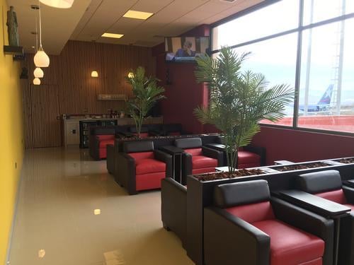 The seating area in the Salones VIP Pacific Club at La Florida Airport features comfortable chairs and a view of the tarmac.
