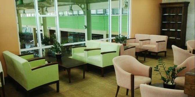 The seating area in Salon Premier at La Romana International Airport features armchairs and tables with views of the terminal.
