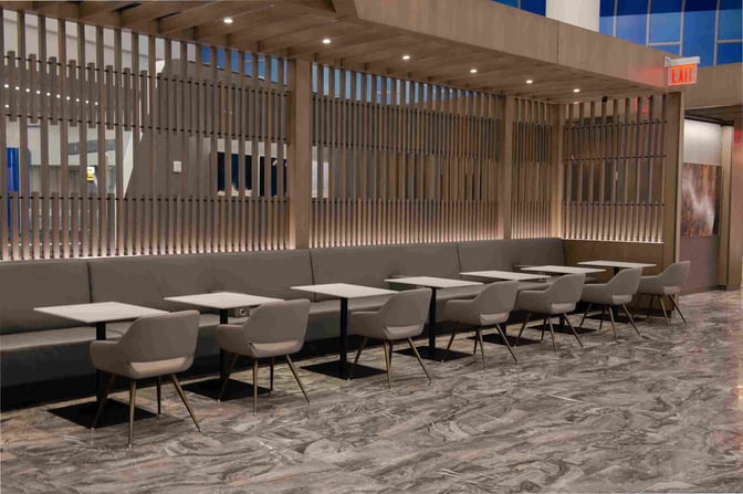 The seating area in the Air Canada Maple Leaf Lounge at LaGuardia Airport features tables with chairs and booth seating.