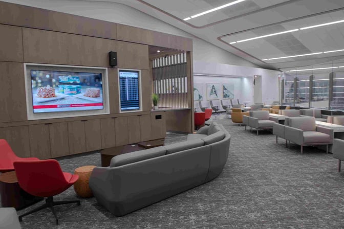 The Air Canada Maple Leaf Lounge at LaGuardia Airport features a seating area with sofas, armchairs, and a display screen showing flight information.