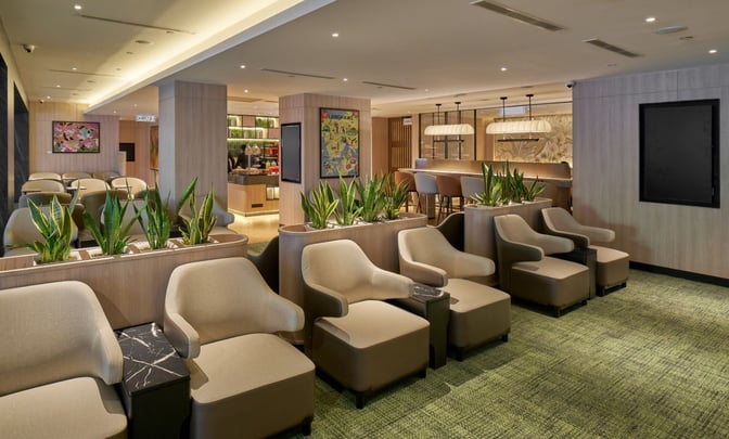 The seating area in Plaza Premium Lounge at Langkawi International Airport features comfortable chairs and a bar with high stools.