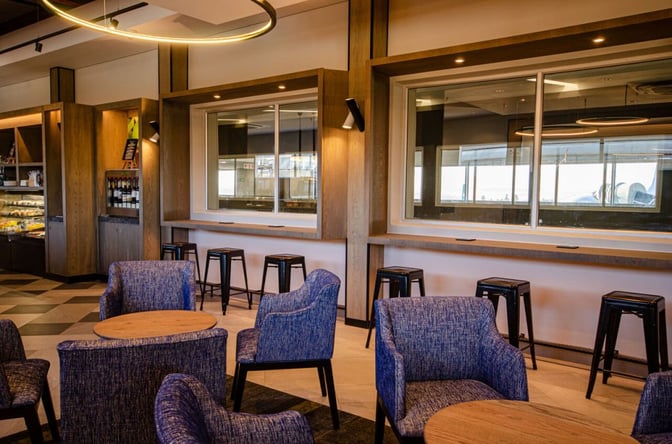The Bidvest Premier Lounge at Lanseria International Airport features seating with tables and a counter area with stools.