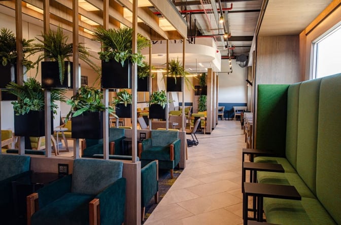 The Bidvest Premier Lounge at Lanseria International Airport features a seating area with armchairs, booth seating, and decorative plants.
