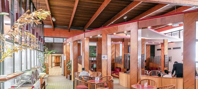 The Samba Lounge at Leon M'Ba International Airport features semi-private seating areas and a self-serve food station along the window.