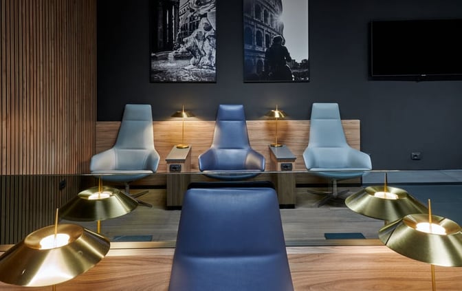 Seating area in Prima Vista Lounge at Leonardo da Vinci-Fiumicino Airport features individual chairs with side tables and reading lamps.