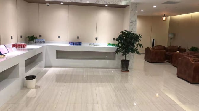 The First Class Lounge at Lhasa Gonggar Airport features a beverage station with assorted drinks and a seating area with sofas.