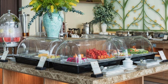 The SH Premium Lounge at Lien Khuong International Airport features a self-serve buffet with covered trays of fresh fruits and vegetables.