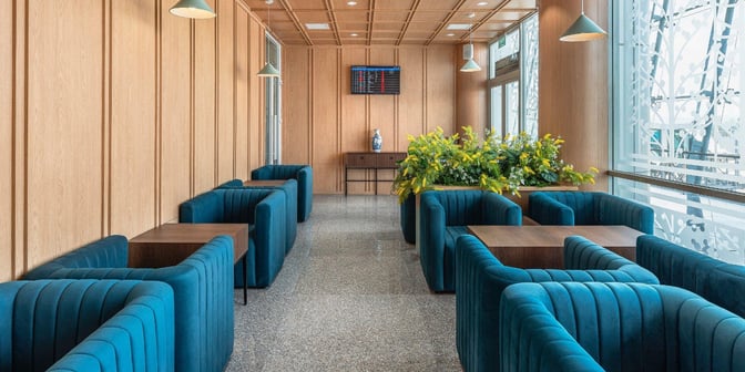 Booth seating at SH Premium Lounge Lien Khuong offers semi-private spaces with tables and a view of the airport.