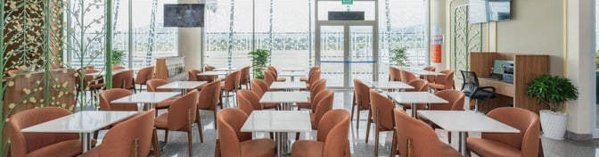 The SH Premium Lounge at Lien Khuong International Airport features a seating area with tables, chairs, and a business station.