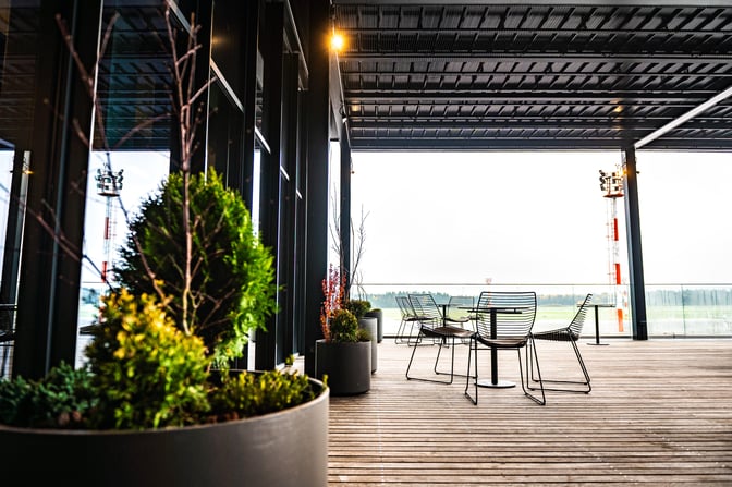 The outdoor seating area at Ljubljana Airport's Business Lounge features wire chairs and tables with views of the tarmac.