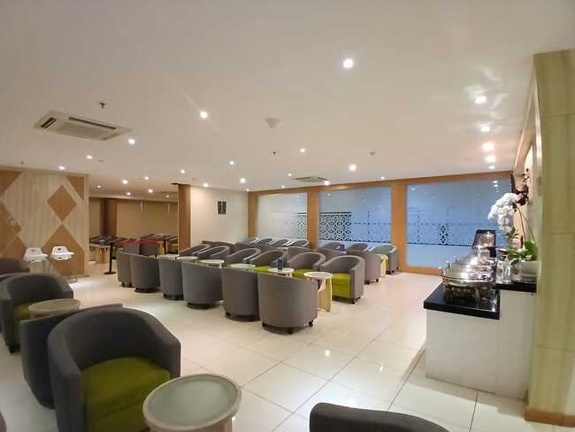 The Concordia Lounge at Lombok International Airport features a seating area with armchairs and a self-serve food station.