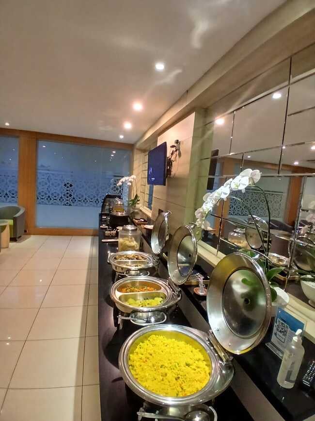The Concordia Lounge at Lombok International Airport features a buffet area with various hot dishes available for self-service.