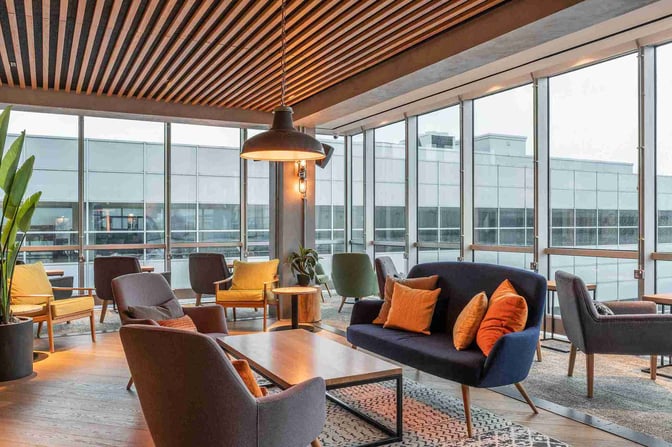 The seating area at My Lounge, London Gatwick Airport, features comfortable chairs and sofas with views of the airport exterior.