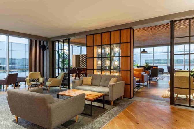The lounge at London Gatwick Airport features a seating area with sofas and armchairs, offering views of the airport.