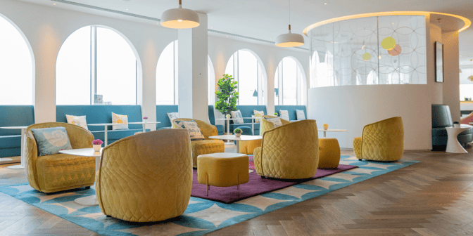 The seating area at Plaza Express Lounge, London Gatwick Airport, features comfortable chairs and tables for relaxation and socializing.