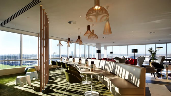 Booth seating in the Plaza Premium Lounge at London Gatwick Airport offers views of the runway through large windows.