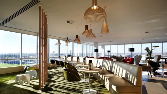 Booth seating in the Plaza Premium Lounge at London Gatwick Airport offers views of the runway through large windows.