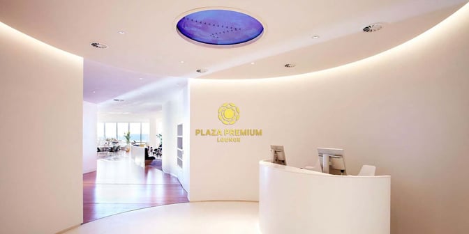 The Plaza Premium Lounge entrance at London Gatwick Airport features a reception desk and leads into a seating area.