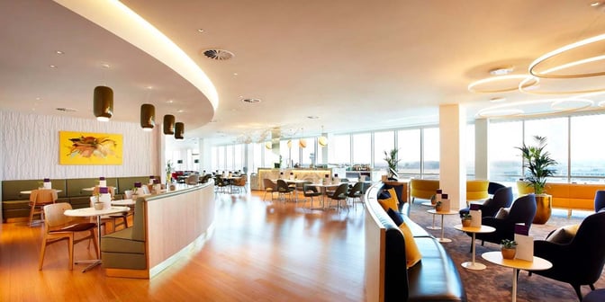 The Plaza Premium Lounge at London Gatwick Airport features a spacious seating area with tables, chairs, and a bar for refreshments.