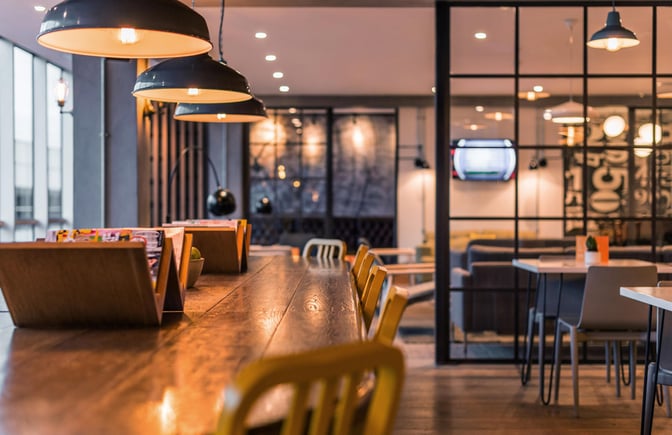 The lounge at London Gatwick Airport features communal tables with magazines and seating, adjacent to a relaxed seating area.