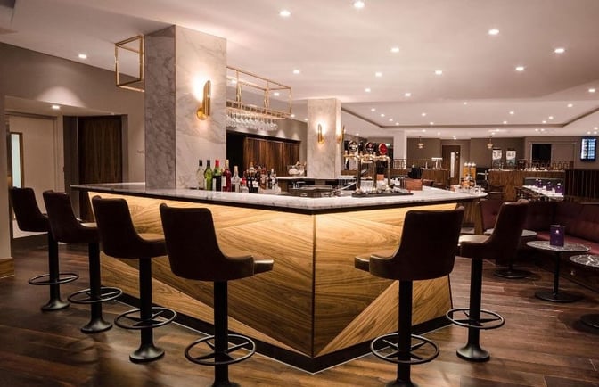 The No1 Lounge at London Gatwick Airport features a bar with counter seating, offering a selection of beverages and snacks.