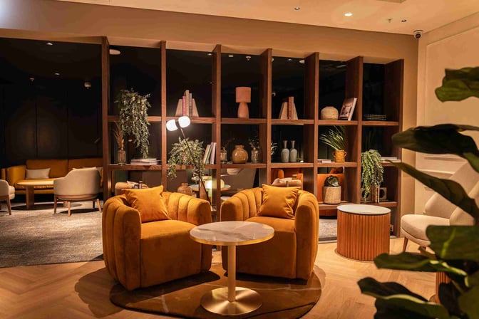 The seating area in No1 Lounge at London Heathrow features comfortable chairs and tables, with decorative shelving and plants for ambiance.