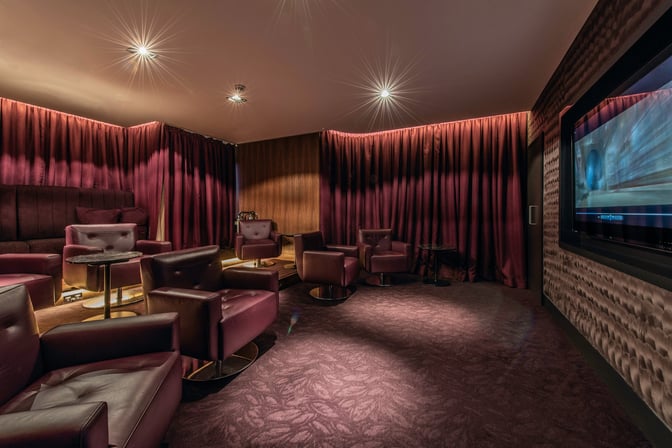 The No1 Lounge at London Heathrow Airport features a seating area with comfortable chairs, small tables, and a large screen for entertainment.