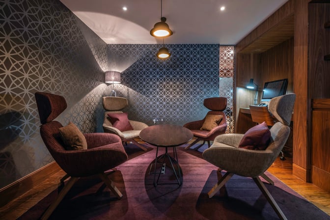 The No1 Lounge at London Heathrow Airport features a seating area with four armchairs around a central table, providing a comfortable space for relaxation.