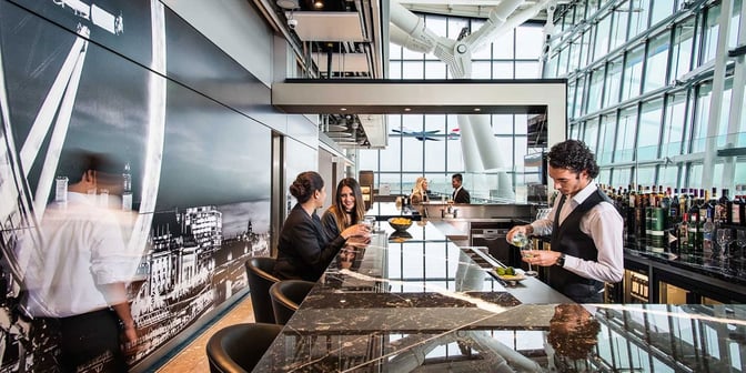 The Plaza Premium Lounge bar at London Heathrow Airport offers a variety of beverages with counter seating and airport views.