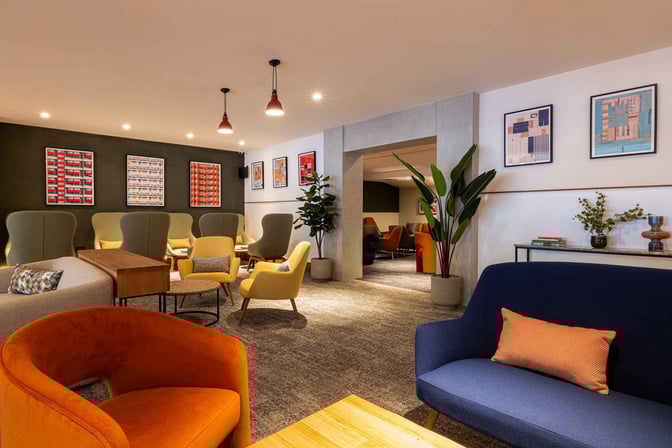 The seating area in My Lounge at London Luton Airport offers a variety of chairs and sofas with decorative wall art.