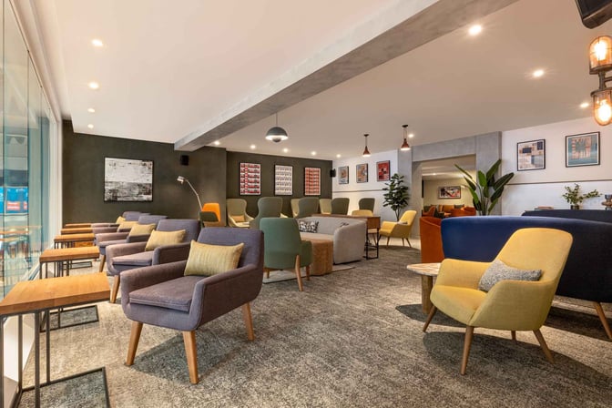 The seating area in My Lounge at London Luton Airport features a variety of armchairs and tables for passenger relaxation.