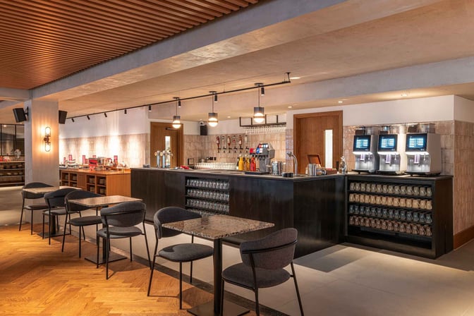 The bar area at My Lounge, London Luton Airport, features self-serve beverage machines and seating for guests.