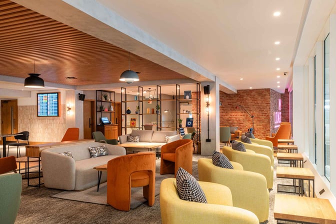 The seating area in My Lounge at London Luton Airport features various chairs and sofas with tables, offering a comfortable waiting space.
