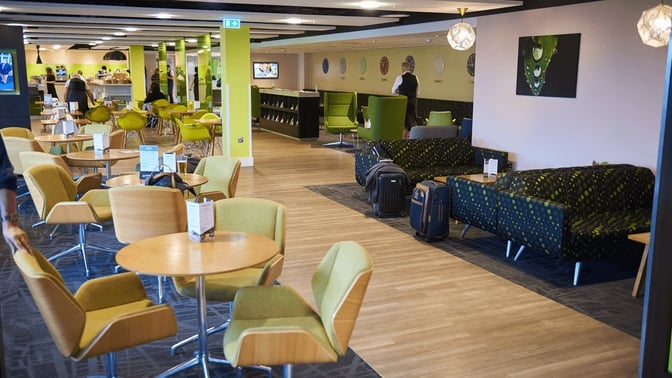 The seating area in the Escape Lounge at London Stansted Airport features tables, chairs, and couches for travelers to relax.