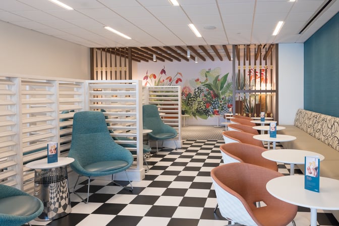 The seating area in the Escape Lounge at Luis Munoz Marín International Airport features individual chairs and tables with partial dividers for privacy.