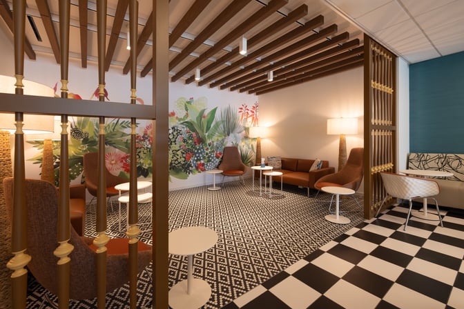 The seating area in the Escape Lounge at Luis Munoz Marín International Airport features comfortable chairs and tables with decorative wall art.