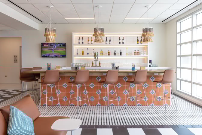 The Escape Lounge at Luis Munoz Marín International Airport features a bar with high stools, offering a selection of spirits and beverages.