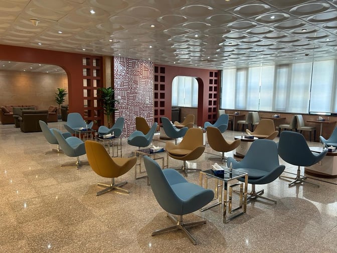 The seating area in Pearl Lounge at Luxor International Airport features swivel chairs and small tables, providing a comfortable waiting space.