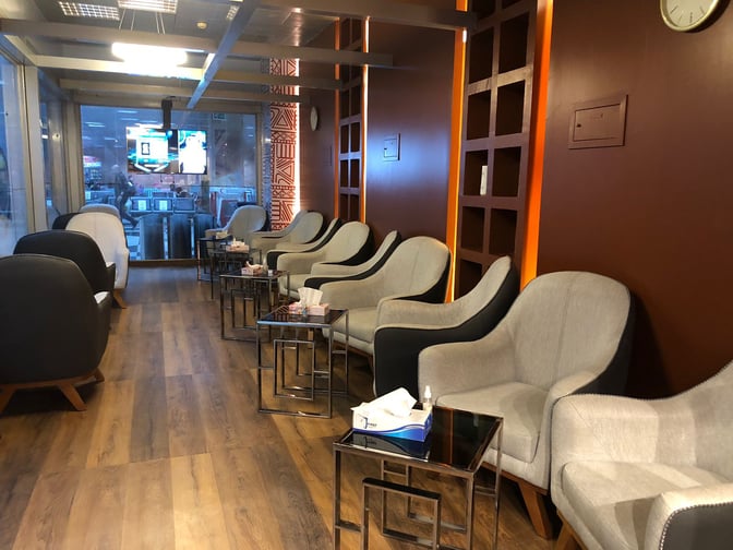 The seating area in the Pearl Lounge at Luxor International Airport features comfortable chairs and small tables with airport views.