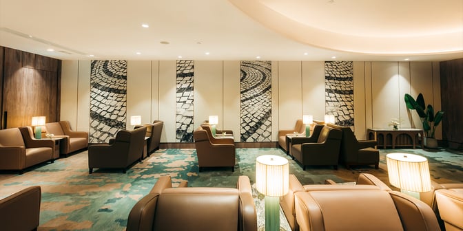The seating area in Plaza Premium Lounge at Macau International Airport features comfortable armchairs with individual lamps and decorative wall panels.