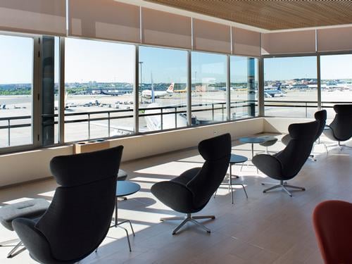 Seating in Sala Cibeles at Madrid Barajas Airport offers comfortable chairs with views of the runway through large windows.