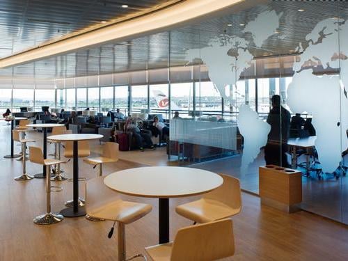 The seating area in Sala Cibeles at Madrid Barajas Airport features tables and chairs with views of the tarmac.